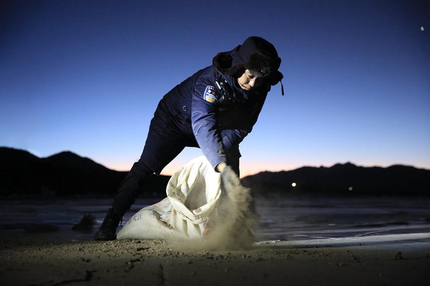 民警在冰面抛洒牛粪炉灰，防止羊群转场摔跤。 彭维熙摄