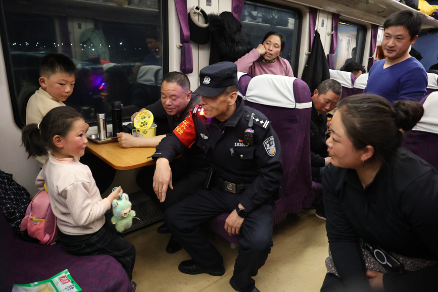 圖為乘警長左紅彬在巡視車廂間隙，向帶孩子的旅客叮囑安全注意事項。黃飛攝