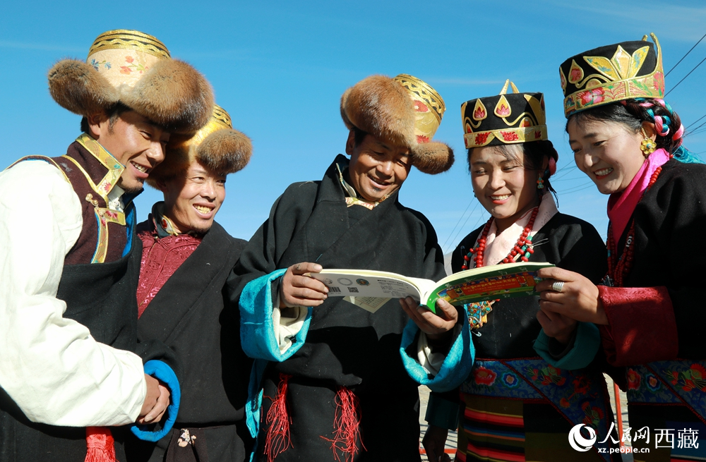 鄉親們身著民族盛裝，圍站在一起認真翻看日歷，共話農事安排與時節規律，笑容洋溢傳遞豐收期盼。人民網記者 吳雨仁攝