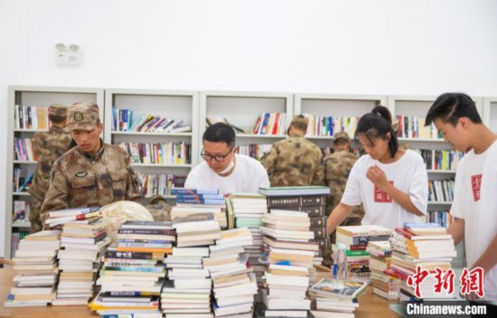 图为志愿者们和边防战士整理图书。　刘晓东 摄